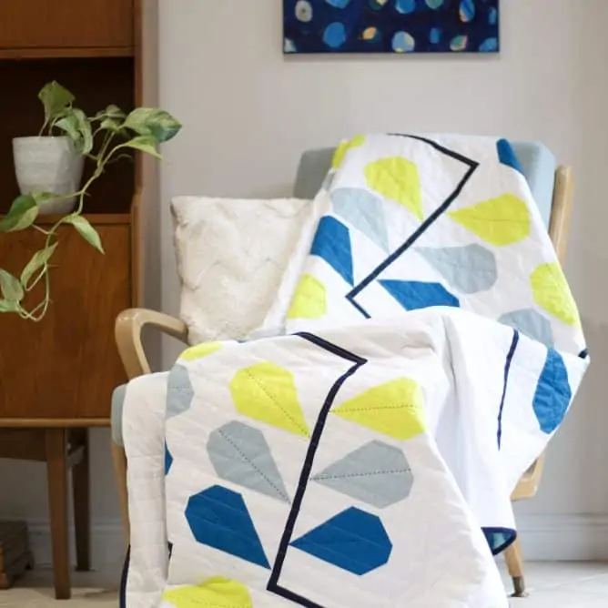 Quilt with plant design draped over chair.